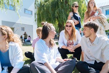 Gruppe Studierende auf der Wiese des Campusinnenhofs