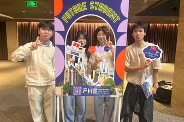 Vier junge Menschen pr&auml;sentieren sich am FHE-Fotoboard &bdquo;Future Student&ldquo; mit Vietnam- und Deutschlandflaggen bei einer Studienmesse.