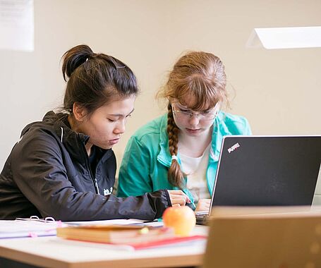 Gruppe Studierende sitzt in der Hochschulbibliothek