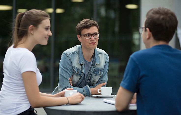 Gruppen Studierende sitzen draußen